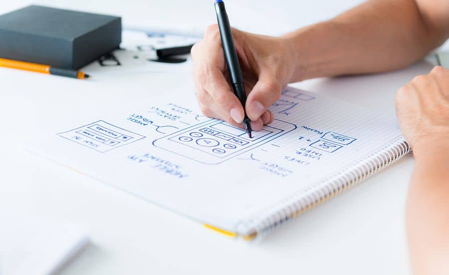 A designer sketching out his mobile app designs on graph paper by hand.