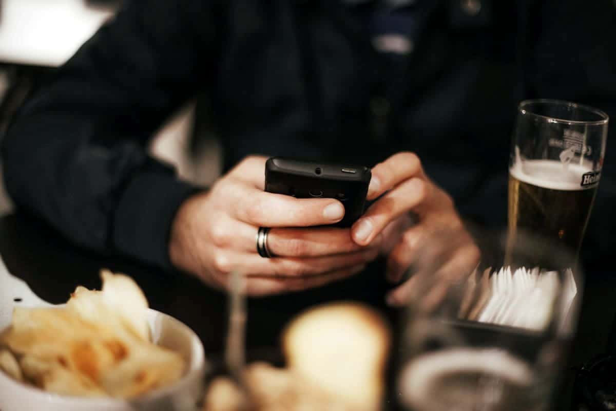 Mobile user tapping on phone while at dinner