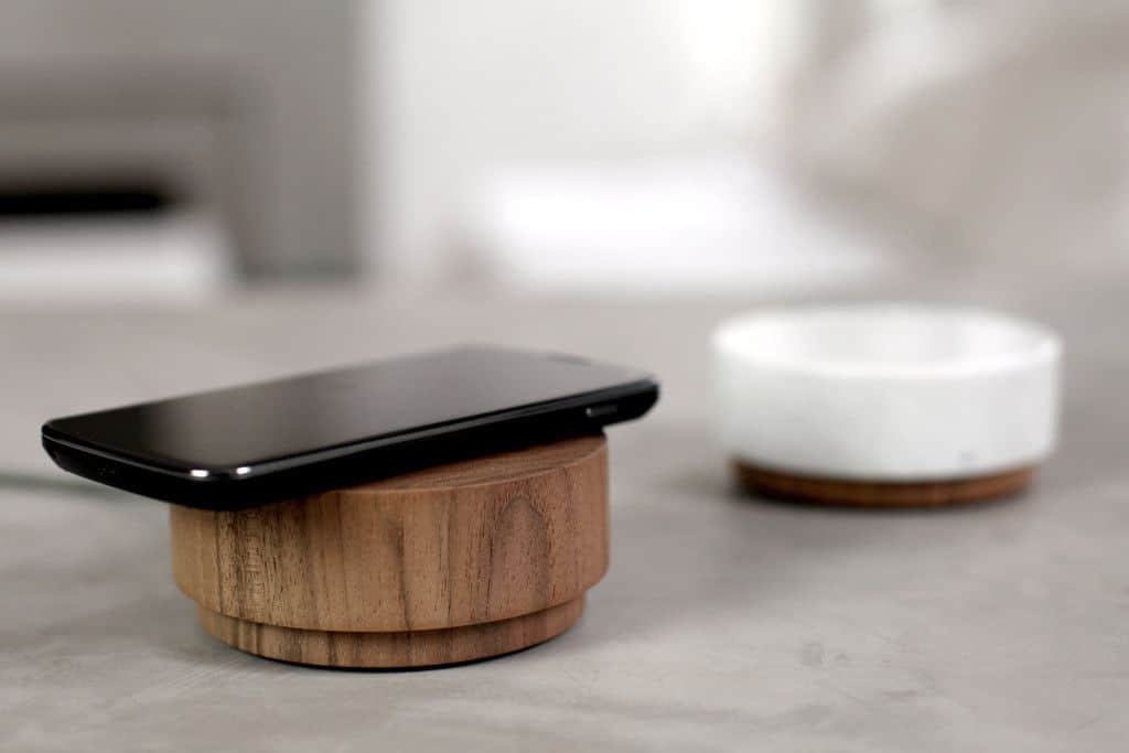 An image of a mobile phone charging while resting on the Pebble wireless charger.