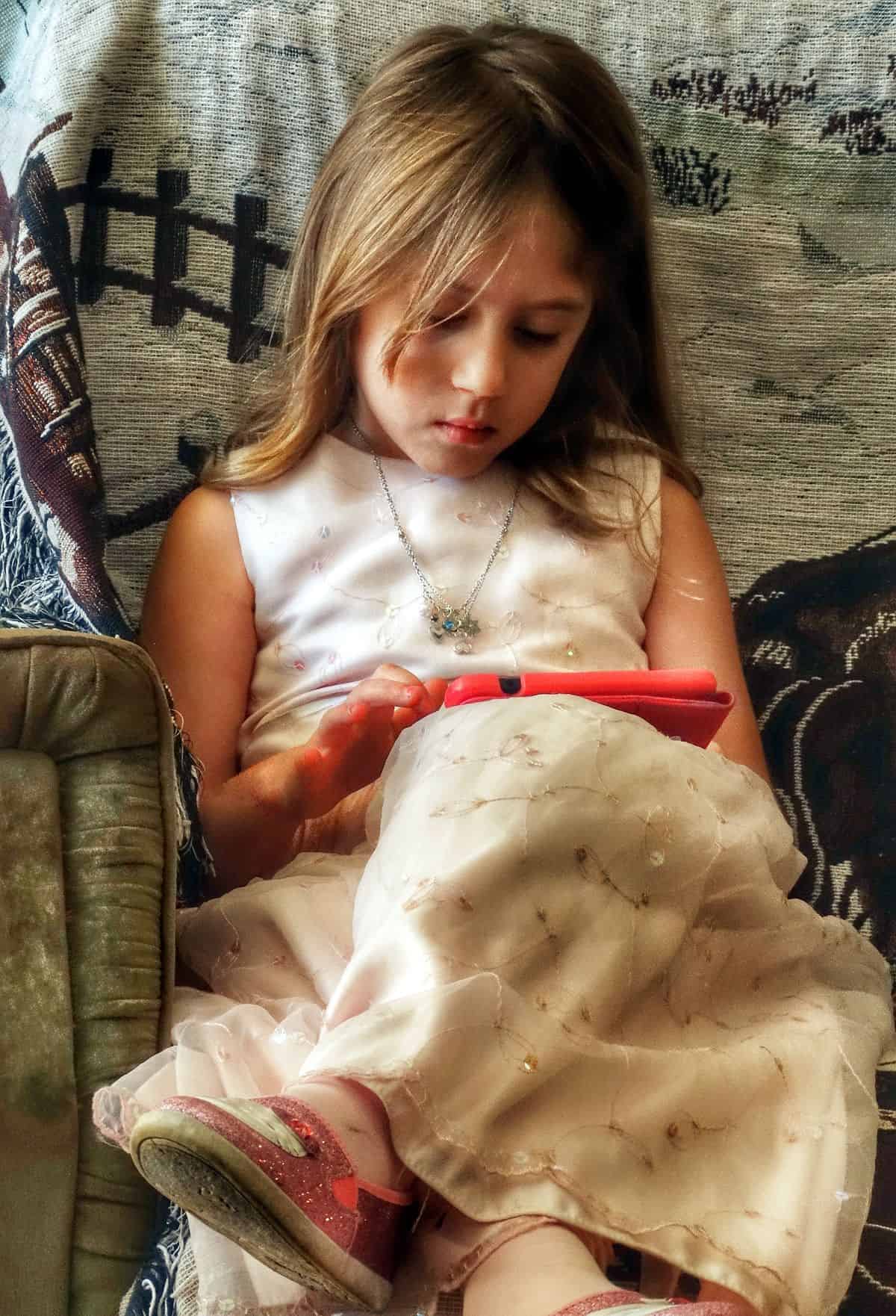 A photo of a young girl using an iPad, demonstrating one of the greatest benefits of accessible mobile UI design: an expanded, more diverse audience for your app.