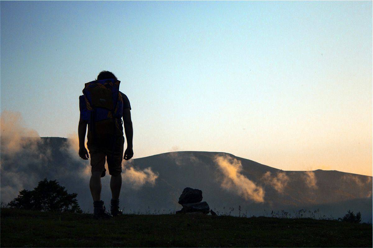 Silhouette of man hiking in the mountains. Your mobile app development team will always be hiking towards progress as professionals.