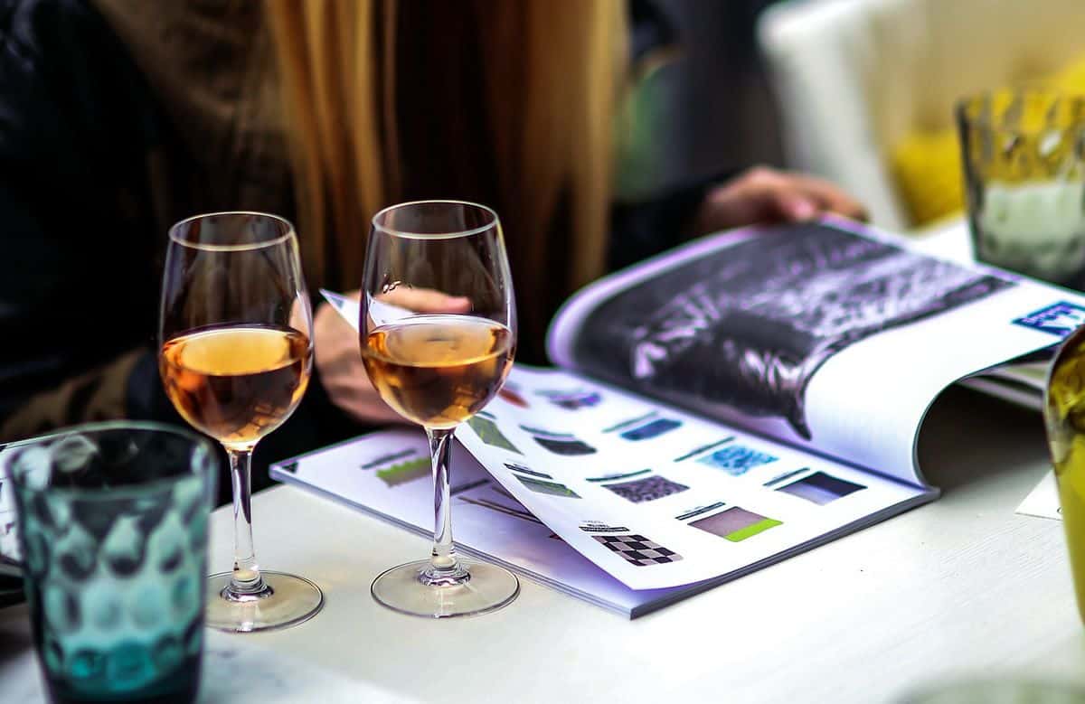Woman looking at magazine with wine glasses on the table. Telling apart great visual design can be like discerning a good wine from an exceptional one.