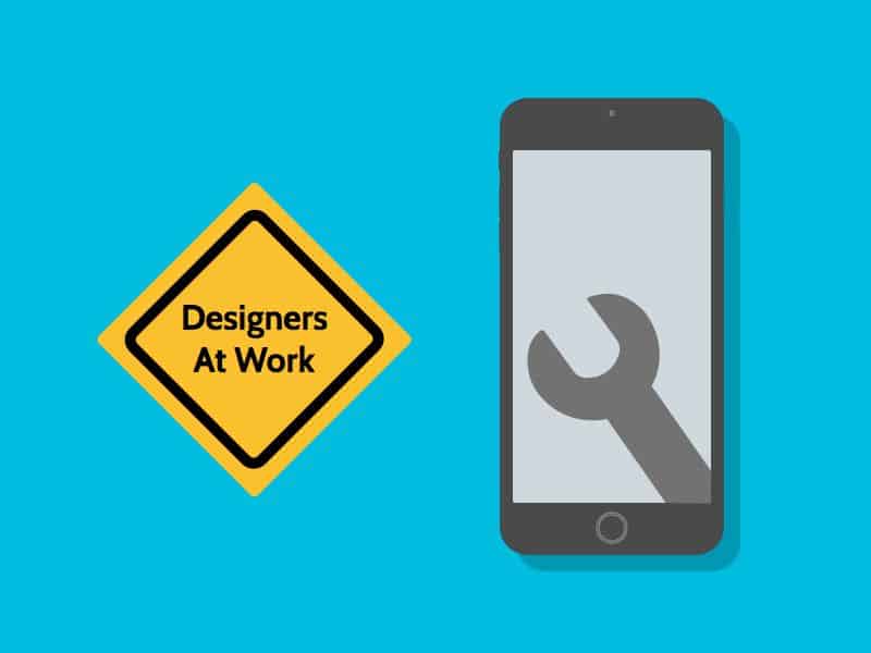 Mobile phone with wrench icon on screen and a keep out sign that says designers at work.