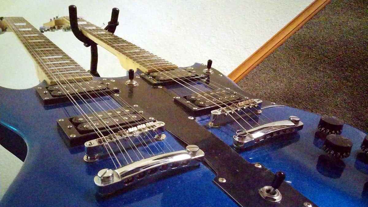 A bottom-up view of a blue double-neck guitar, one neck with six strings and the other with 12.