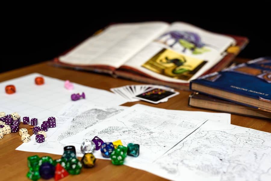 Maps, cards, open books, and multi-sided dice on the table of a tabletop RPG player. What if we could combine the magic of RPGs with the world of fitness apps?