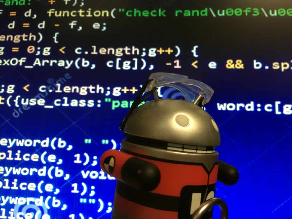 A metal Android figurine in front of a screen of mobile app code.