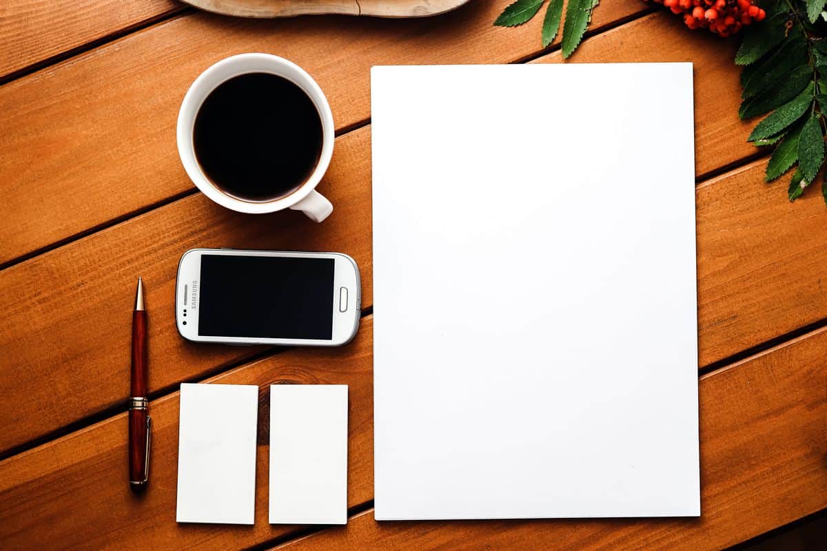 A photo of a desk with a smartphone, a cup of coffee, two blank notecards and a blank white sheet of paper. As SketchSheets proves, sometimes the best iOS templates are literal blank slates.