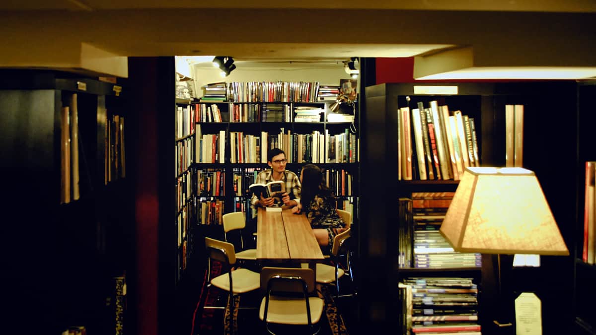 Two students discuss user interface design at a table in a college library.