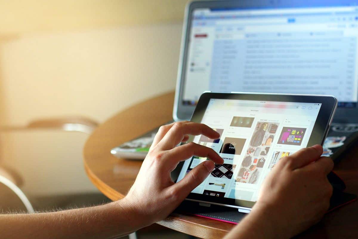 Close up of a person's hands using a table with a laptop computer in the background.