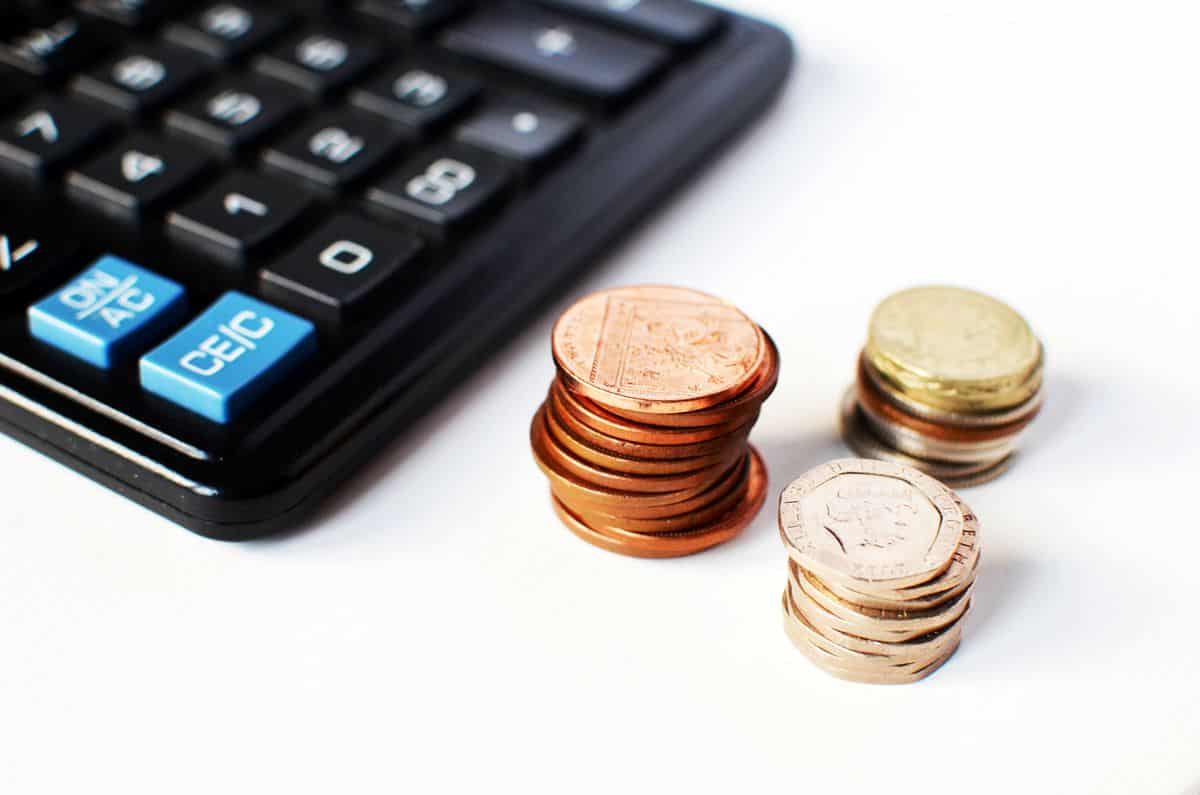 Three piles of US coins and a calculator in the background.