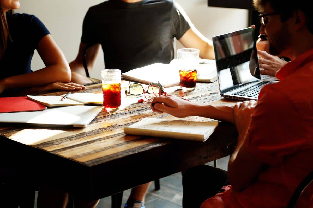 A product design team sits around a desk, notebooks open and coffee flowing.