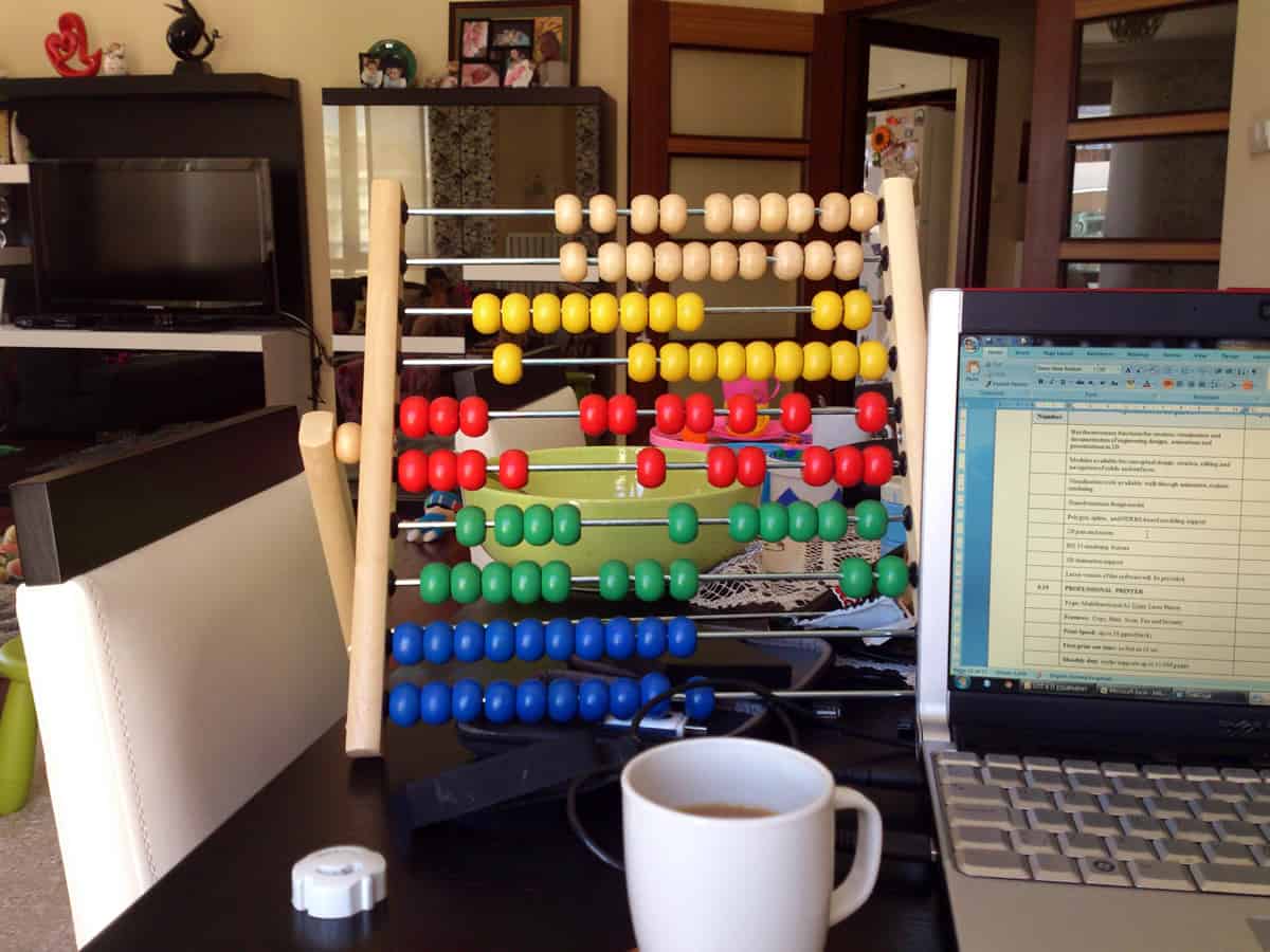 A photo of a toy abacus sitting next to a laptop on a desk. Abacus rings dating back to the 17th century prove wearable computing is even older than we think.