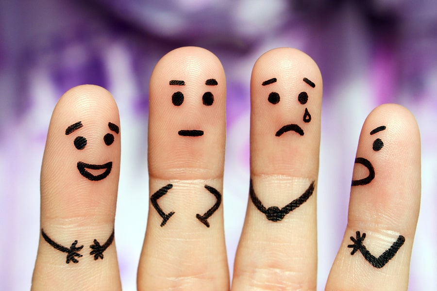 A close-up of four fingers, each depicting a different marker-drawn emotion.