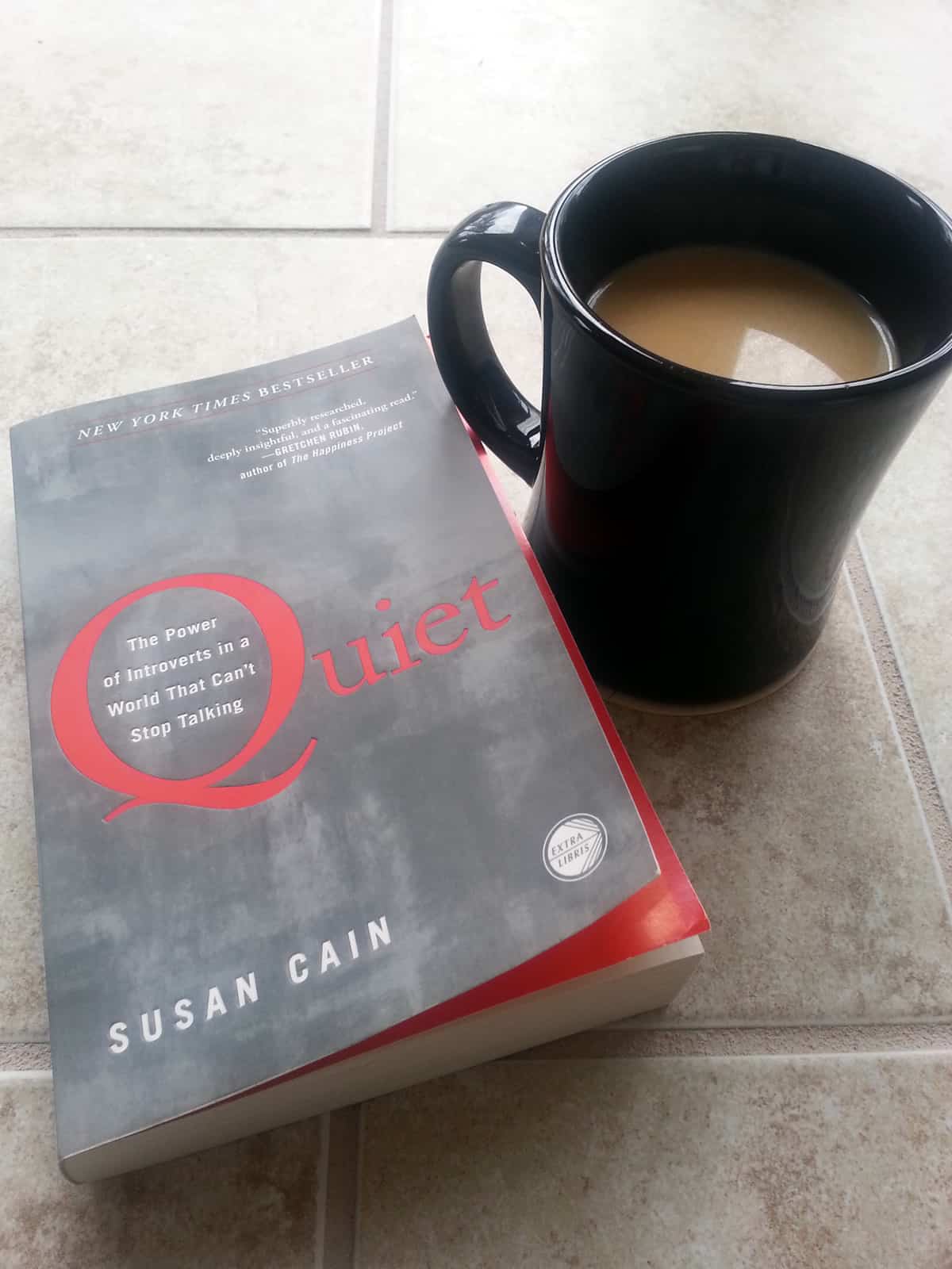 A close-up of a book by Susan Cain entitled Quiet: The Power of Introverts in a World That Can’t Stop Talking next to a cup of coffee.