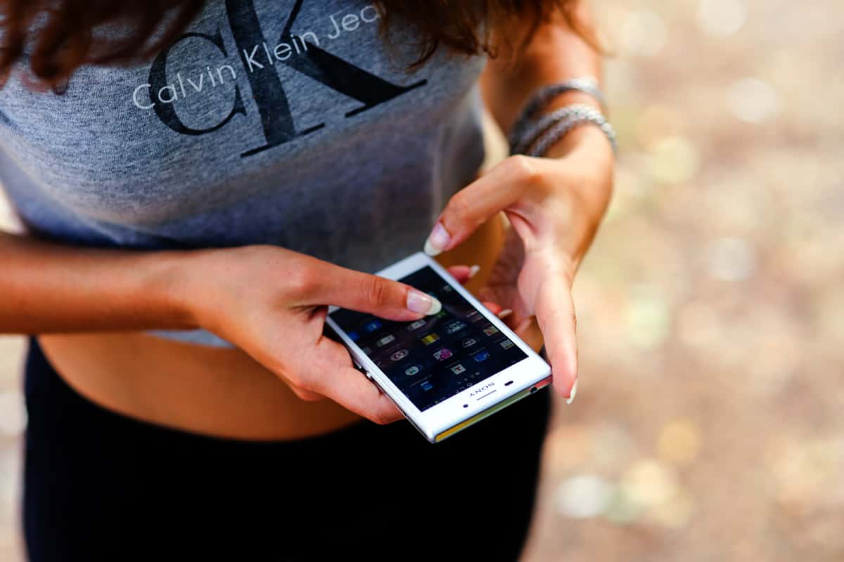 Young woman in a Calvin Klein Jeans t-shirt using a Sony mobile phone.