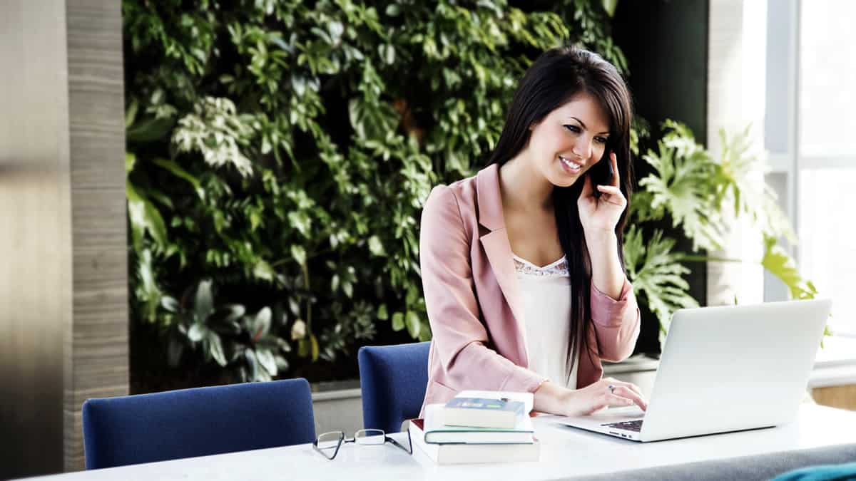 A designer talking to a client on the phone while referring to her laptop.