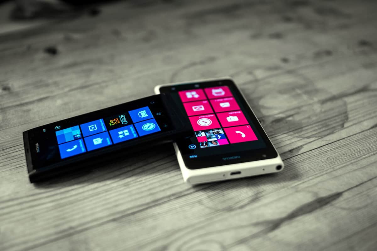 A photo of two Windows Phones, which helped popularize flat mobile app design, on a wood table.