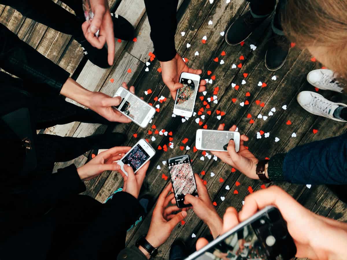 A photo of seven people in a circle using their mobile devices to take pictures.