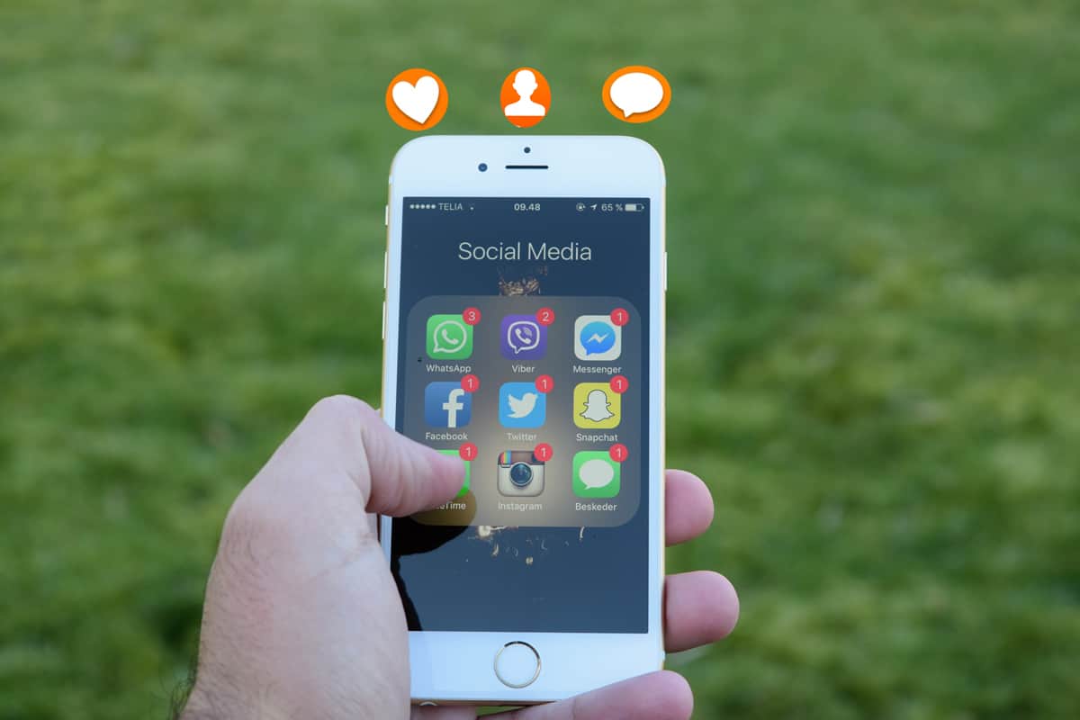 A photo of an iPhone displaying multiple social media app icons in a person’s hand.