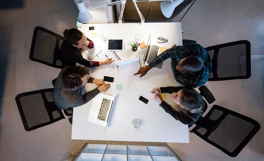 A photo from above of four people working together around a white table.