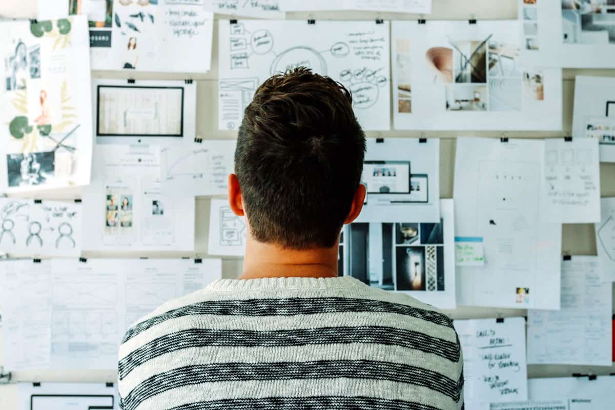 A photo of a man looking at a wall full of design ideas.