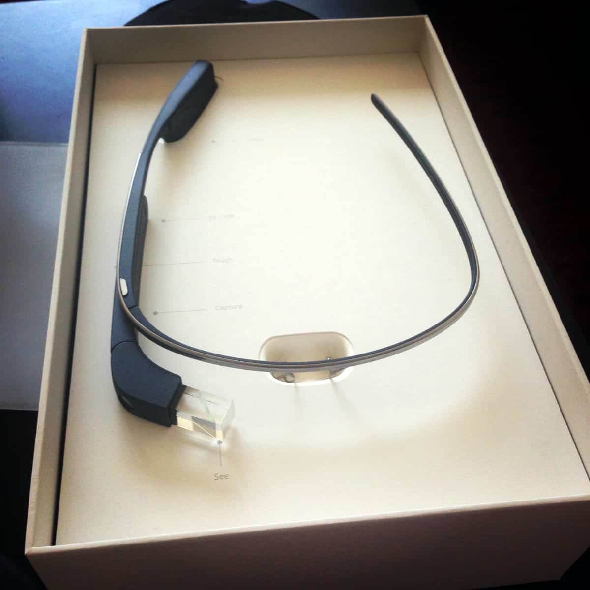 A picture of an early version of Google Glass sitting in a shallow box.