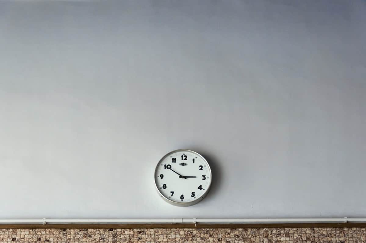 Image of a clock on a bare gray wall.