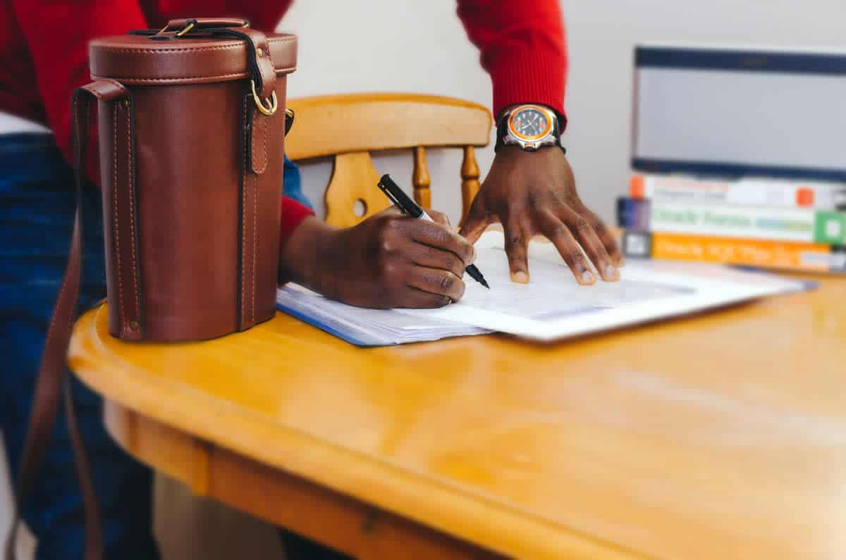 Image of a person signing a contract on a table.