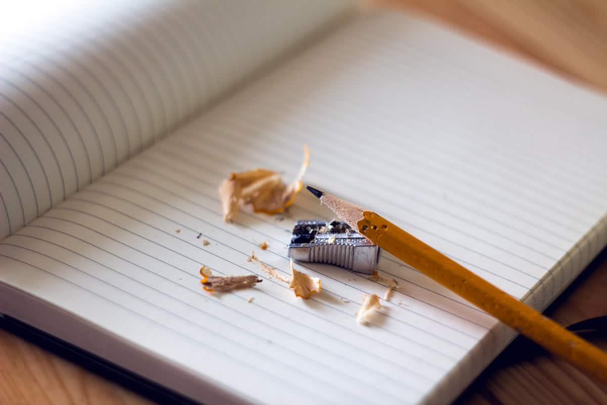 Image of a pencil being sharpened on top of a notebook.