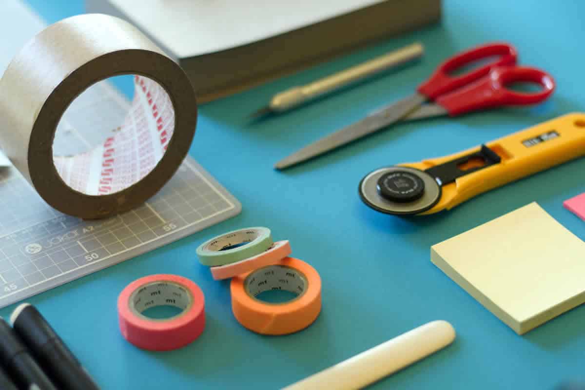 Image of tools on a table including tape, sticky notes, and scissors