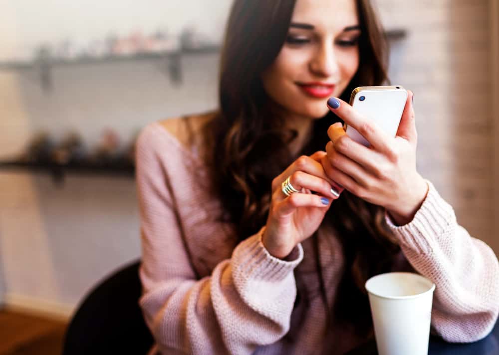 A photo of a woman communicating with a chatbot on a mobile device.