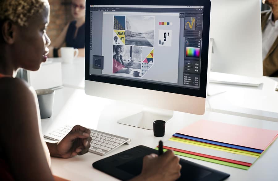 A photo of a woman using Adobe Illustrator on a computer.