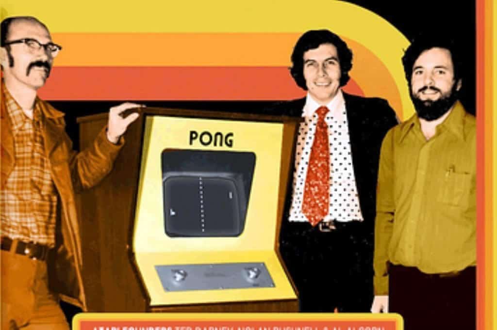 A photo of the creators of Pong next to a Pong game cabinet.