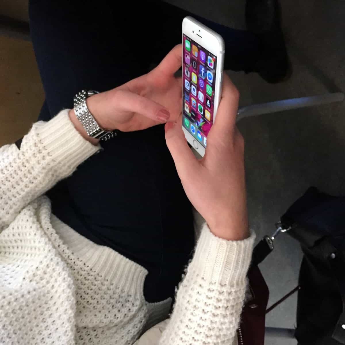 A photo of a woman holding a silver iPhone in her hands.
