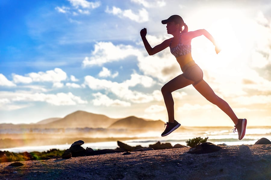 A photo of a woman running on a sunny day near water.