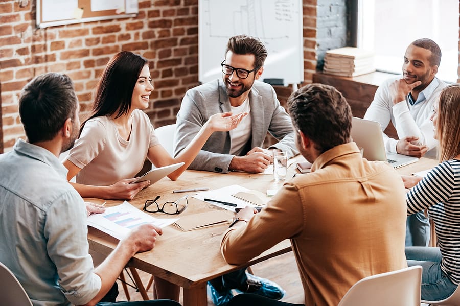 A photo of a work team conversing during a meeting.