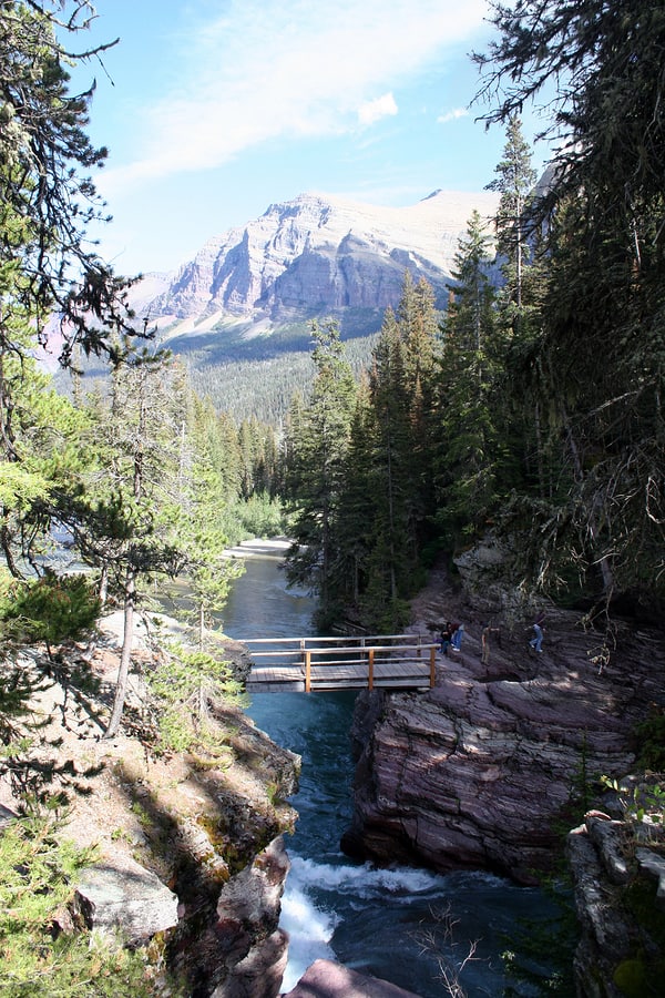 A photo of St. Mary’s Falls in Glacier National Park with giant mountains in the background.