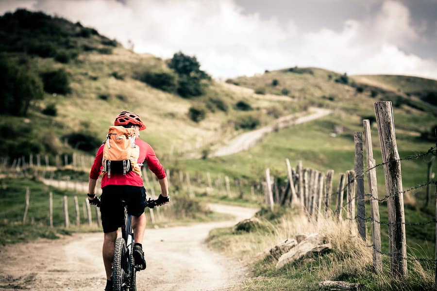 A photo of a man in a red helmet and jacket riding a bicycle down a trail. In visual design, color can be used to highlight new or important elements.