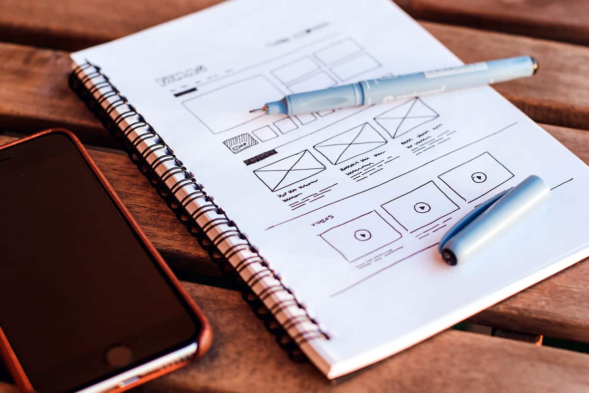 Image of a notebook and pen with a low fidelity wireframe.