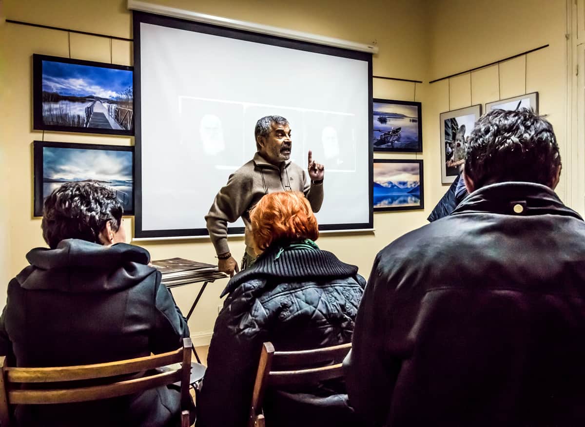 A photo of a professor giving a lecture in front of a projector screen.
