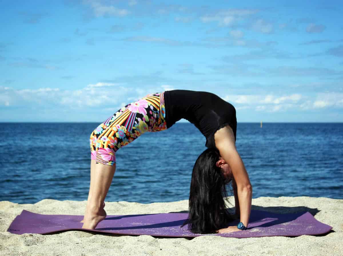 A photo of a woman doing yoga on a beach.