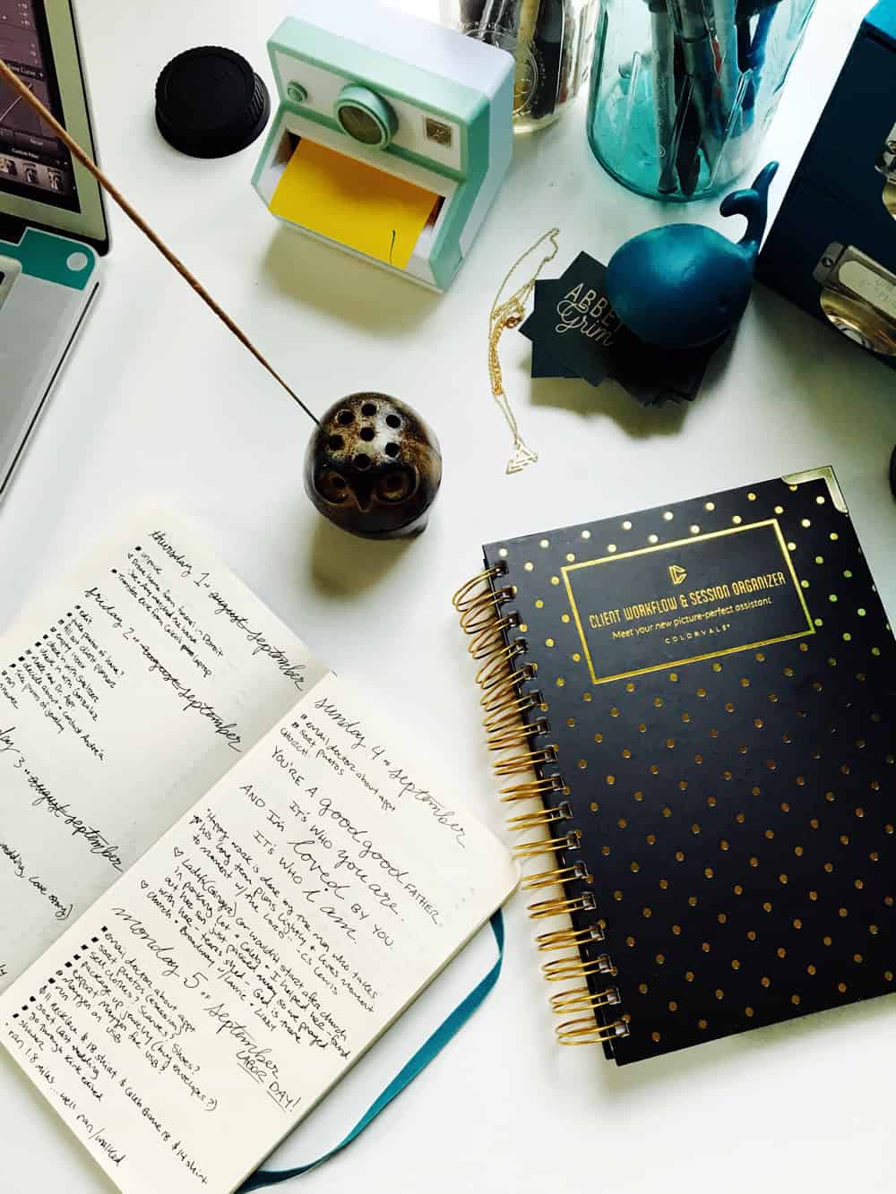 A photo of a journal on a desk next to a laptop and client organizer.