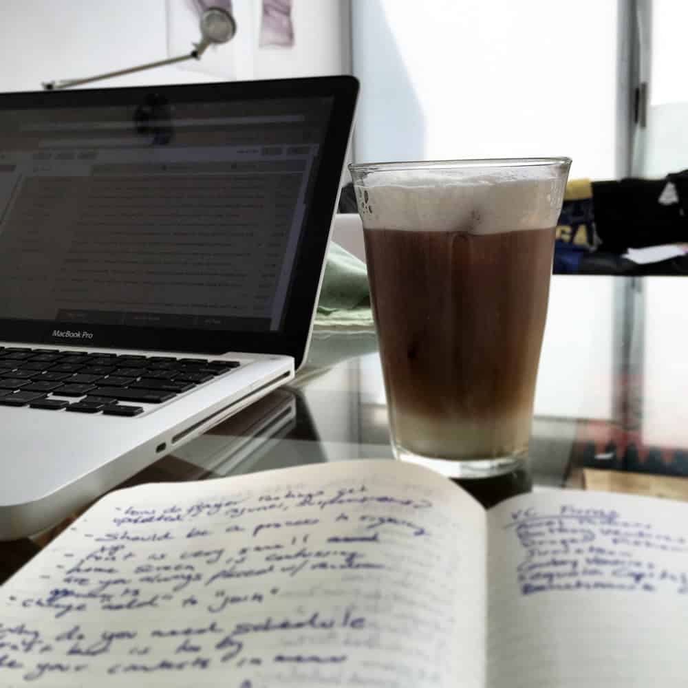 A photo of a journal full of to-dos next to a laptop and fresh latte.