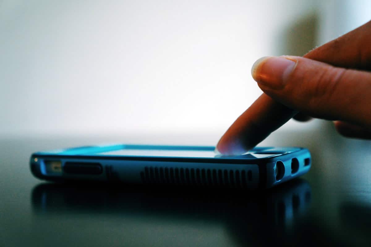 A photo of a woman’s finger touching the screen of her iPhone.