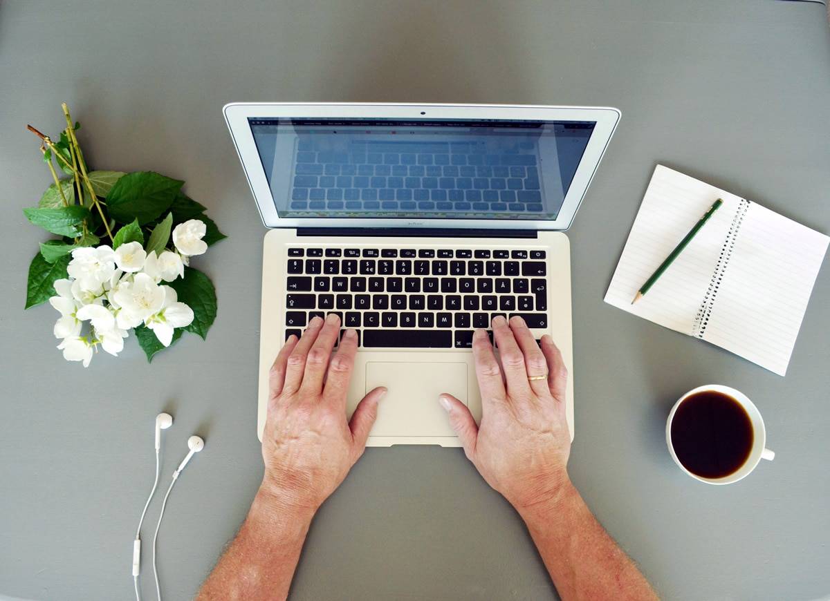 A photo of a man working on a laptop at his very clean, minimalist desk.