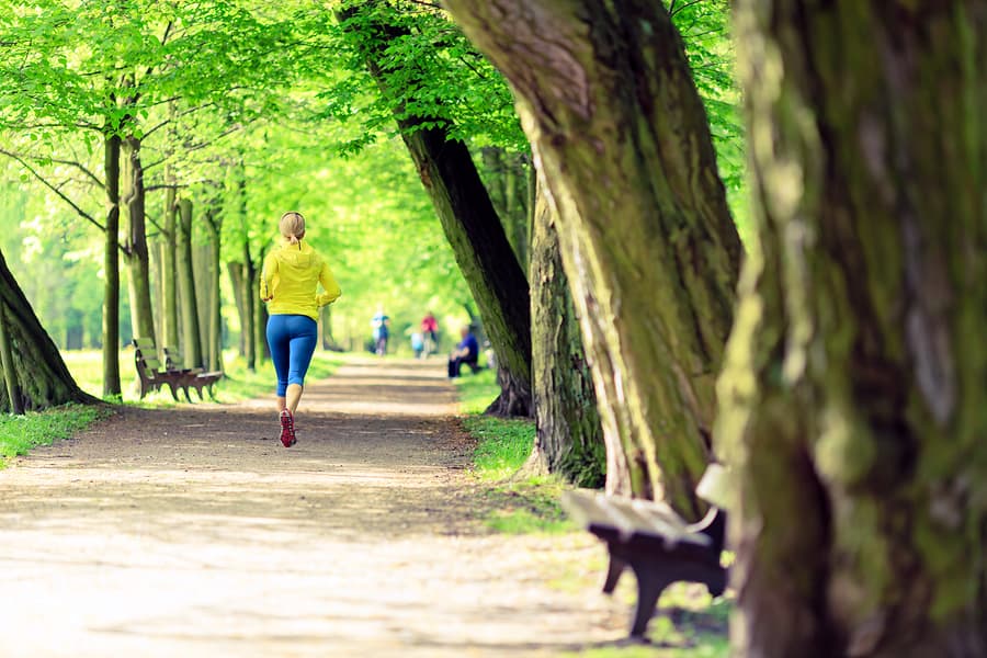 A photo of a woman running in the park on a beautiful spring day.