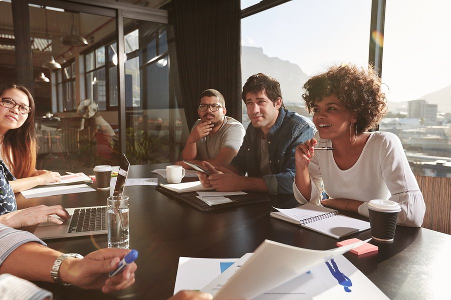 A photo of a few team members having mixed reactions to what their team leader is saying.