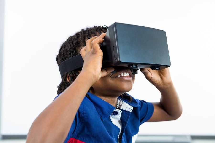 A photo of a child wearing a virtual reality headset with a big smile on his face.