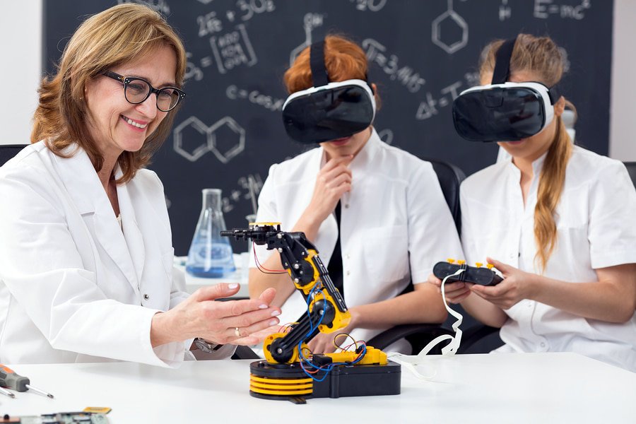 A photo of two students using virtual reality and a remote control to operate a robotic device in a classroom.