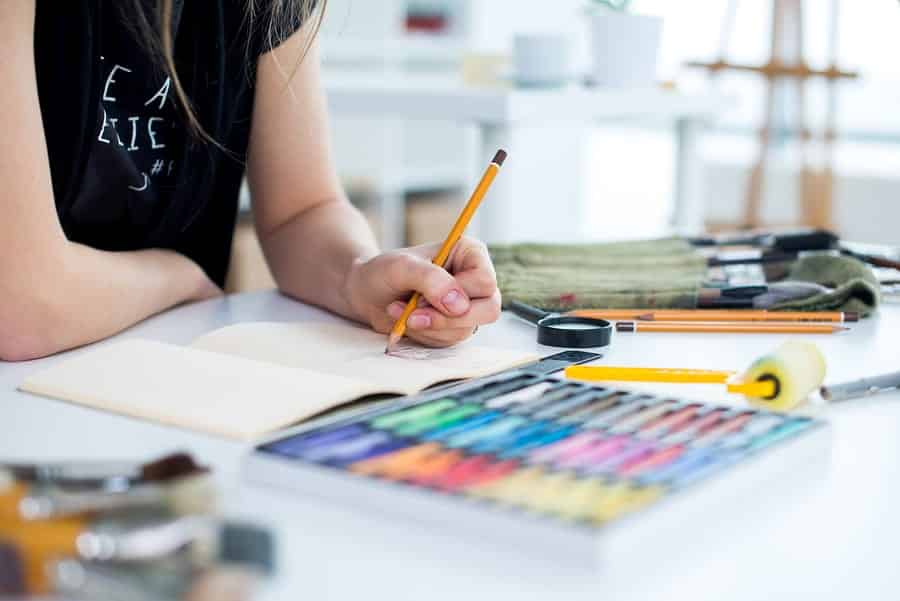 A photo of an artist sketching with colored pencils.